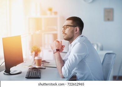 Business, People And Technology Concept - Businessman In Glasses Sitting At Office Computer And Thinking