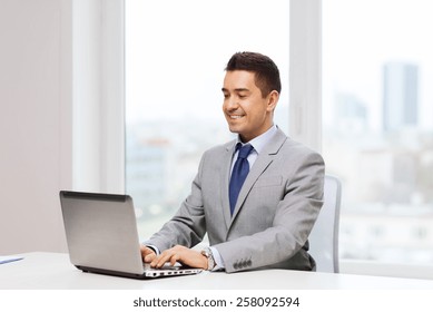 business, people and technology concept - happy smiling businessman in suit working with laptop computer in office - Shutterstock ID 258092594