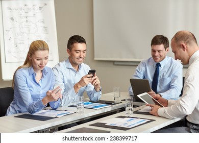 business, people and technology concept - smiling business team with smartphone and papers meeting in office - Powered by Shutterstock