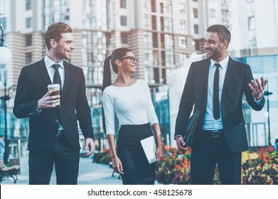 Business People. Three Cheerful Young Business People Talking To Each Other While Walking Outdoors