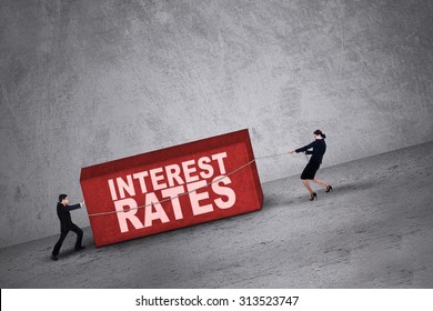 Business people trying to get a block with interest rates word on it