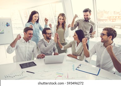 Business people are using gadgets, raising hands in fists and smiling during the conference - Shutterstock ID 593496272
