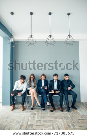 Business people waiting for job interview holding phones and notepad