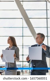 Business People Waiting While Holding Blank White Placard In Arrival Area At Airport