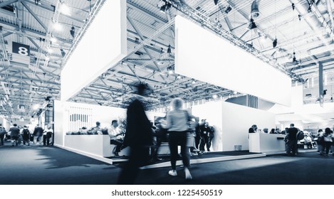 Business People Walking Between Trade Fair Booths At A Public Event Exhibition Hall, With Banner And Copy Space For Individual Text 