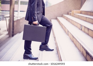 Business People Walking On Street In The City,After Office Work.In Front Of Corporate Building.Businessman Walking Quick Steps.Some Person Hold Business Briefcase Go Down From Stairs. Business Travel 