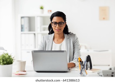 business, people, work and technology concept - happy smiling businesswoman with laptop computer at office