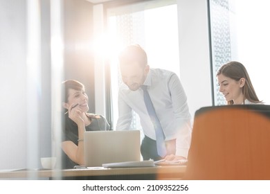 Business People Working At Laptop In Sunny Conference Room Meeting