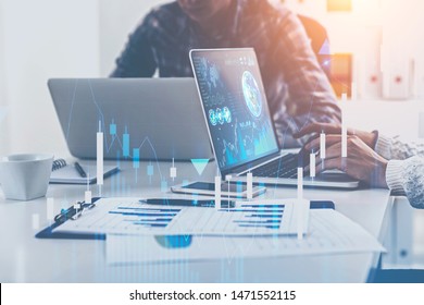 Business people working with laptops in blurred office with double exposure of business infographics and graphs. Market analysis concept. Toned image. Elements of this image furnished by NASA - Powered by Shutterstock