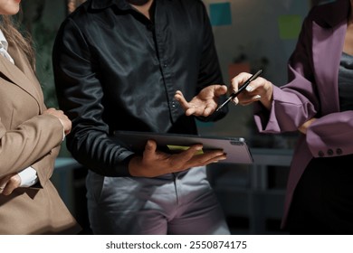 Business people working late in office, discussing project on tablet, focusing on strategy and planning. Diverse team collaborating effectively, brainstorming ideas for success using technology - Powered by Shutterstock