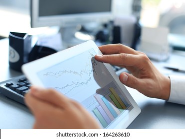 Business person analyzing financial statistics displayed on the tablet screen 