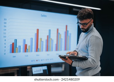 Business person analyzing sales statistics on tv screen at the office. He is working on improving the company profitability. - Powered by Shutterstock