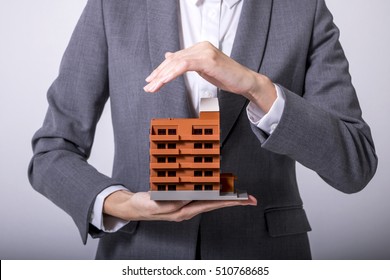 business person holds apartment building miniature model