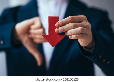 Business person holds red arrow and shows thumb down