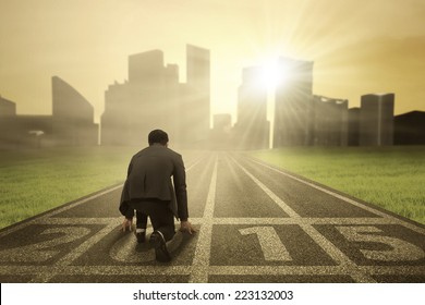 Business person in ready position on track for running and chasing his aim