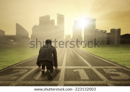 Business person in ready position on track for running and chasing his aim