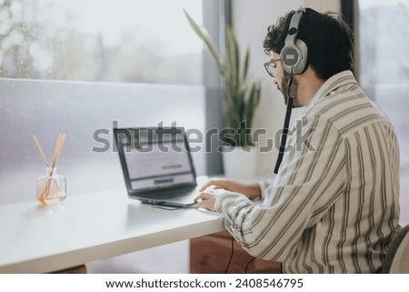 Business person sitting on working desk next to the window working on lap top. Copy space.