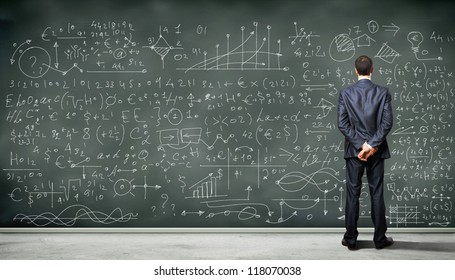 Business Person Standing Against The Blackboard With A Lot Of Data Written On It