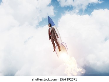 Business Person In Suit Launching Upwards On Rocket. Progress And Innovation Technology. Corporate Employee Flying With Jetpack Rocket In Stratosphere. Leadership Motivation And Goal Achievement.