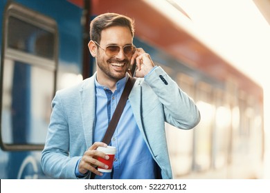 Деловой человек ждет поезда и разговаривает по телефону.