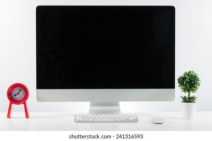 Business place of work with with computer monitor keyboard and accessories on table on white wall
