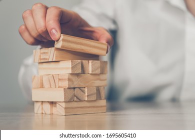 Business plan concept - hands build a tower of wooden blocks. Close up.