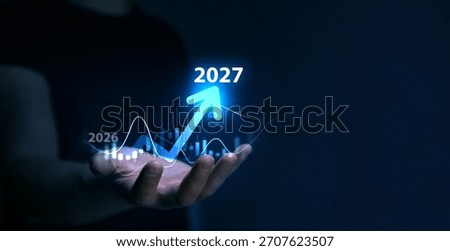 Business plan for increase in 2027 year.Development to success and motivation in new year 2027. Business person draws increase arrow graph corporate future growth year 2026 to 2027.