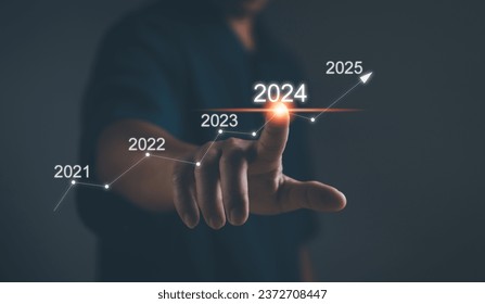 Business plan and vision for 2024. Startup for business. Performance goals for growth ,Businessman uses his finger to kick the 2024 graph showing marketing strategies for the annual business plan.
