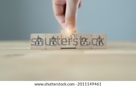 Business planning , strategy and problems solving to find solution.Key unlocking to achieve goals and mission. Man hold wood cubes with unlock key and keys icon on table; grey background. Copy space.