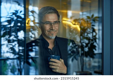 Business portrait - businessman looking through window in office, smiling. Mature age, middle age, mid adult man in 50s with happy confident smile. Copy space. - Powered by Shutterstock