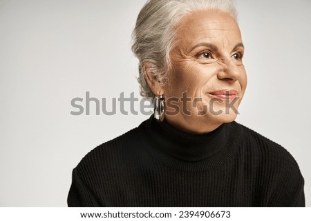 business portrait, happy middle aged business woman in turtleneck looking away on grey backdrop