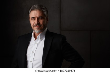 Business Portrait Of Happy Older Man In 50s With Gray Hair Against Dark Background. Businessman Smiling, Copy Space.