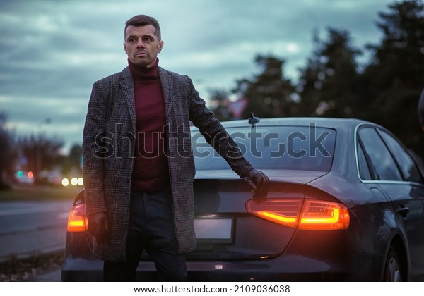 Business portrait of a man in front of a\
car. Stylish and handsome guy in the\
cityscape.