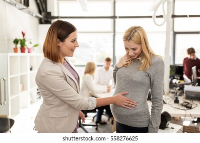 business, pregnancy and people concept - happy colleague touching pregnant woman belly at office - Powered by Shutterstock