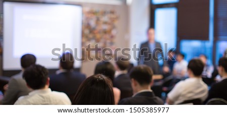 Business presentation being given by executive manager. Corporate seminar with expert speaker presenting to people. Presenter giving speech during lecture. Leadership training coach in workshop.

