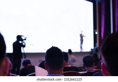 Business Presentation At A Corporate Conference. Audience Listens To Speaker Giving Public Speech On Stage At Global Executive Symposium.