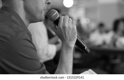 Business Presentation At A Corporate Conference. Audience Listens To Speaker Giving Public Speech On Stage At Global Executive Symposium. Black And White.
