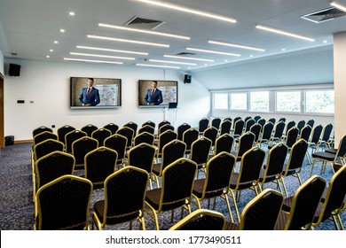 Business Presenter Joining A Seminar Via Video Conference Call In Empty Convention Center. 