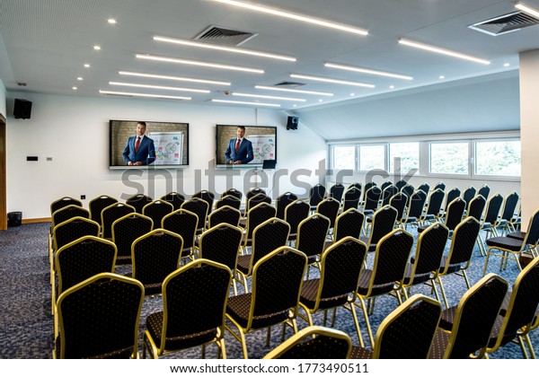 Business presenter joining a seminar\
via video conference call in empty convention center.\
