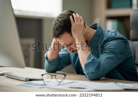 Business Problems. Desperate Young Businessman Sitting At Workplace In Office, Touching Head, Suffering From Bankruptcy And Financial Crisis, Having Headache Or Luck Of Inspiration, Copy Space