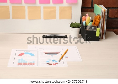 Business process planning and optimization. Documents with different types of graphs and stationery on wooden table