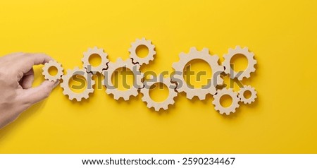 Business process and workflow automation with flowchart. Hand holding wooden cog flowing process management on yellow background