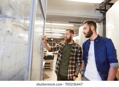 Business, Production And People Concept - Men Writing On Whiteboard At Brewery Or Non-alcoholic Beer Plant