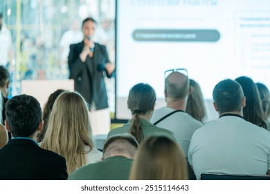 Business professional giving presentation to engaged audience in a modern conference setting. Focus on communication and learning. - Powered by Shutterstock