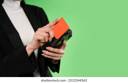 A Business Professional Interacts With a Card on a Sleek Device Against a Vibrant Green Backdrop - Powered by Shutterstock