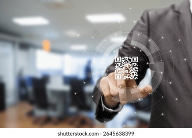 A business professional in a suit is pointing at a digital QR code in a modern office. The background shows blurred office furniture and a tech-focused environment.
