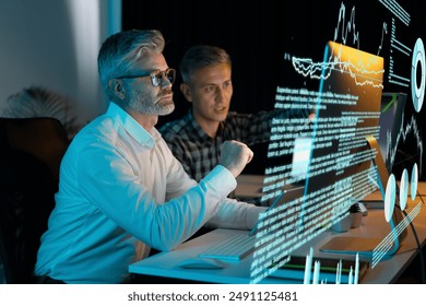 Business Professionals Analyzing Digital Data At Night, Showcasing Teamwork, Technology, And Innovation In A Modern Office Environment. - Powered by Shutterstock