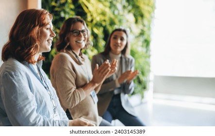 Business professionals applaud and celebrate a successful meeting. The office environment is filled with teamwork and collaboration as colleagues network and work together towards common goals. - Powered by Shutterstock