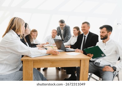 Business professionals engaging in teamwork, using laptop and documents, during a productive meeting in a modern office