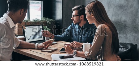 Photo of Business professionals. Group of young confident business people analyzing data using computer while spending time in the office